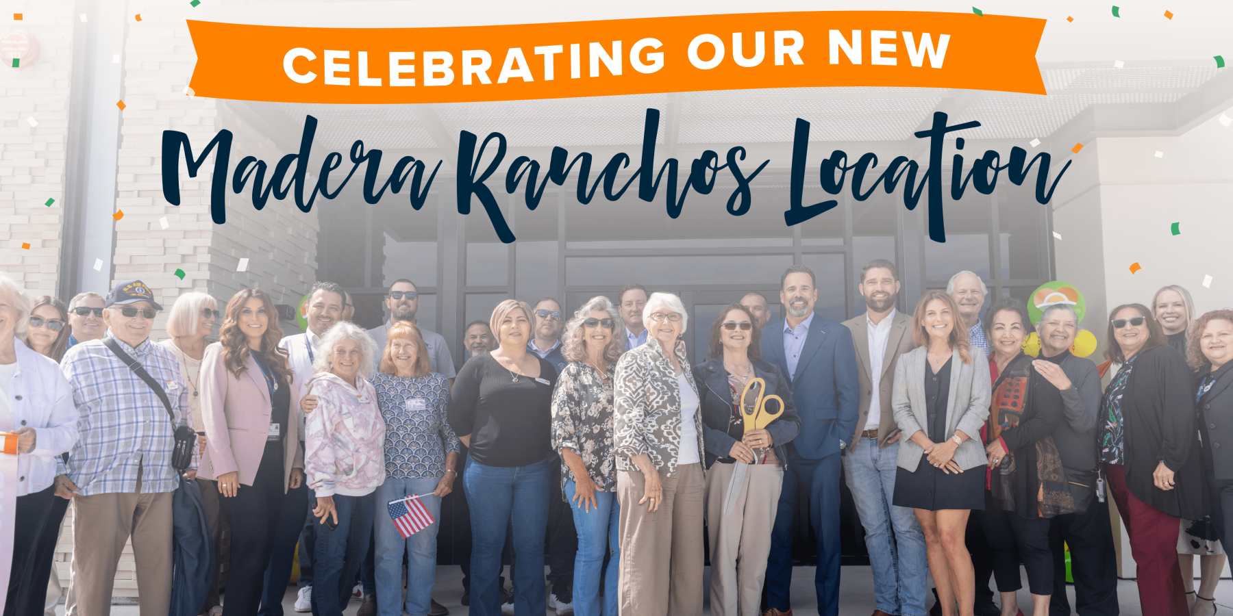 Ranchos Ribbon Cutting-blog Un gran grupo de personas sonríe delante de un edificio bajo una pancarta que dice: "Celebramos nuestra nueva sede en Madera Ranchos". Al fondo cae confeti.